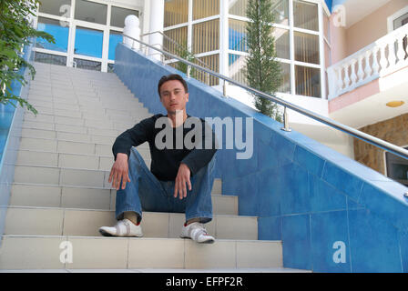 Young man sitting on the stairs of modern building Stock Photo