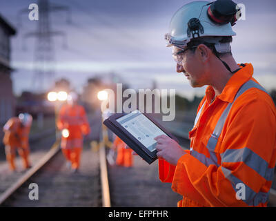 Railway maintenance worker using digital tablet at night Stock Photo