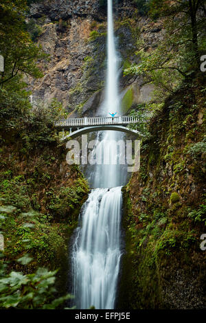 Male hiker crossing footbridge over Multnomah Falls, Oregon, USA Stock Photo