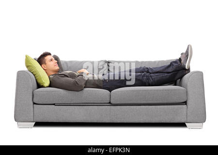 Pensive young guy laying on a sofa isolated on white background Stock Photo