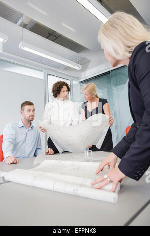 Colleagues discussing blueprints in office Stock Photo