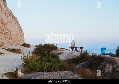 Young woman sitting on clifftop bench looking out to sea, San Clemente, California, USA Stock Photo