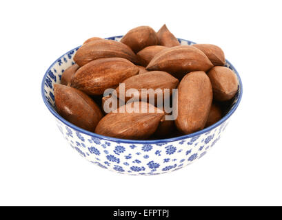 Pecan nuts in shells, in a blue and white porcelain bowl with a floral design, isolated on a white background Stock Photo