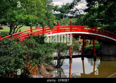 Singapore:  A traditional orange wooden arched bridge spans a lagoon in the tranquil classical Japanese Garden Stock Photo