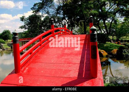 Singapore:  High arched orange traditional wooden bridge spans a lagoon at the sublime classical Japanese Garden Stock Photo