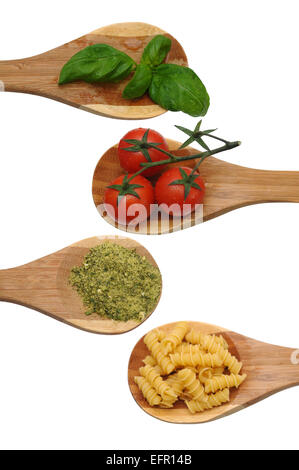 Wooden spoons with basil, tomatoes, herbs and pasta Stock Photo