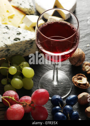 Different types of cheeses with wine glass and fruits. Stock Photo