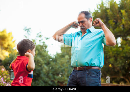 Grandfather and grandson flexing arms in garden Stock Photo