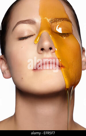Female model's face partially covered in honey Stock Photo