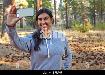 Young woman in forest taking smartphone selfie, Los Angeles, California, USA Stock Photo