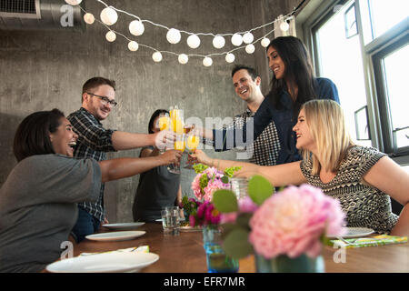 Group of friends around table,  raising glasses, making toast Stock Photo