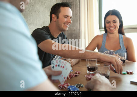 Group of friends playing cards around table Stock Photo