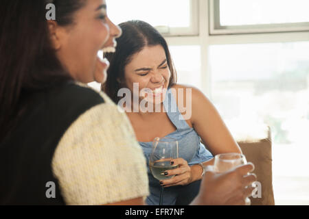 Two female friends sitting on sofa, drinking wine Stock Photo