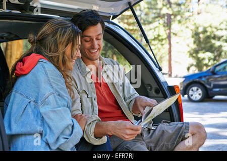 Young couple sitting on car boot looking at map, Los Angeles, California, USA Stock Photo
