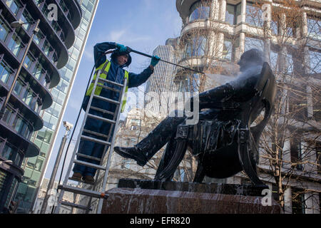 London, UK. 9th February, 2015. Surrounded by modern offices near the Bank of England, in Cornhill, a conservator with City of London contractor Rupert Harris Conservation, uses a pressure jet spray to hose off the statue of Victorian philanthropist, entrepreneur and banker George Peabody (1795 to 1869). As part of a continual programme of maintenance and cleaning by the Square Mile's governing Corporation, historic items - from hundreds of statues and plaques to other pieces of historic value are regularly attended to. Stock Photo