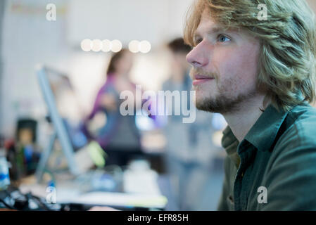 A man looking up from his task in a computer repair shop. Stock Photo