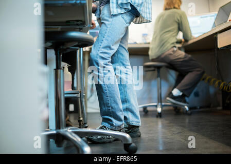 Two people at a computer repair shop. One seated and one standing. Stock Photo