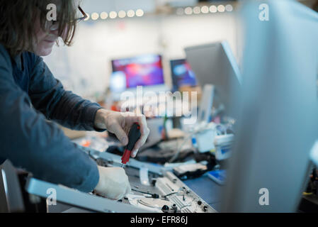 A m an using a screwdriver on the circuit boards of a computer. Repair technician. Stock Photo