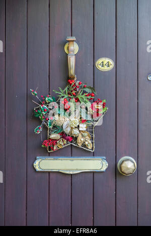 Christmas decorative wreath hung on front door knocker Stock Photo