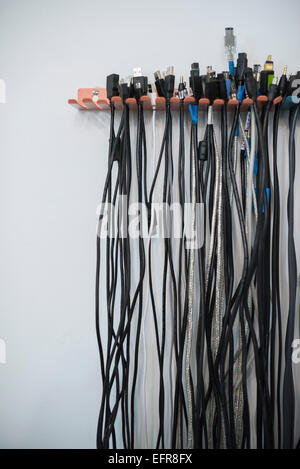 Cables arranged in rows on a wall rack. Stock Photo