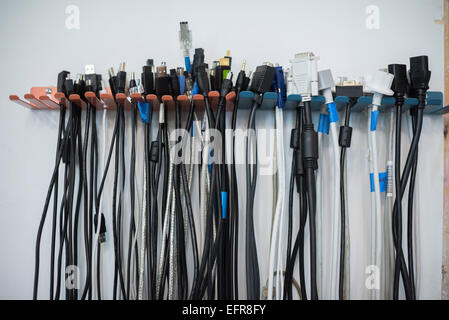 Cables arranged in rows on a wall rack. Stock Photo