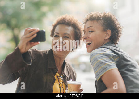 Two mature female friends taking smartphone selfie on street Stock Photo