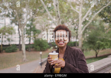 Portrait of smiling mature woman drinking takeaway coffee in park Stock Photo