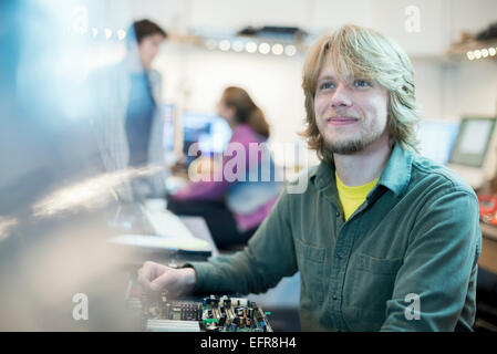 A young man and two colleagues working in a computer shop. Stock Photo