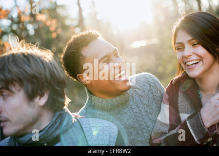 Smiling couple standing in a sunlit forest in autumn. Stock Photo