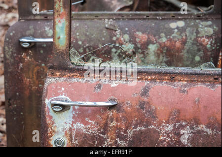 An abandoned vintage car becomes a deteriorating sculpture of rusted metal, faded paint, broken glass and resilient chrome. (USA) Stock Photo