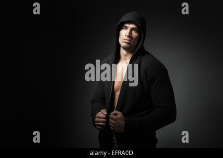 strong man wearing hoodie isolated on black background with copyspace Stock Photo