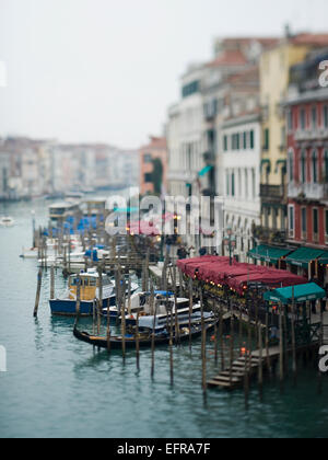 Wide canal in Venice, with boats and traditional gondolas moored along the waterfront, and restaurants and cafes. Stock Photo