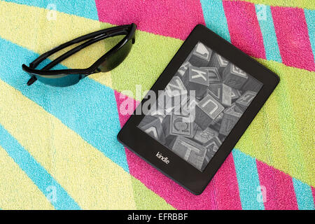 Kindle Paperwhite on a beach towel with sunglasses Stock Photo
