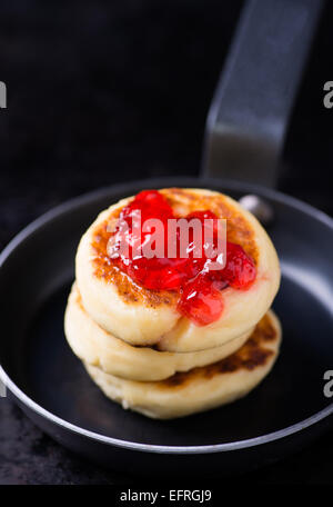 Cottage cheese pancakes with currant jam in pan, selective focus Stock Photo