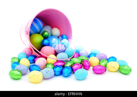 Pink Easter pail spilling colorful chocolate eggs and candy Stock Photo