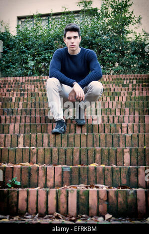 Handsome young man sitting outdoor on old brick stairs Stock Photo