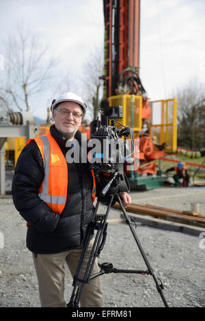 A documentary filmmaker poses with his camera on location at and oil rig in New Zealand Stock Photo