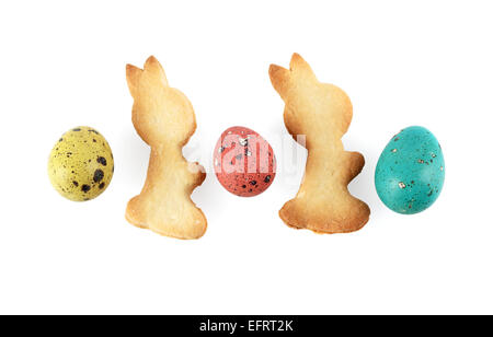 Multicolored painted quail eggs and biscuits in the shape of rabbits on a white background. Isolated with clipping path. Stock Photo