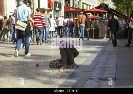 Woman begging on Avenue des Champs-Elysees in Paris, France. Stock Photo