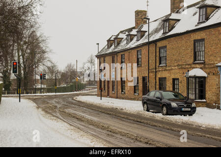 Whittlesea Road Thorney in the snow winter Thorney church place of worship cars and street in the snow snowy weather in Thorney Stock Photo