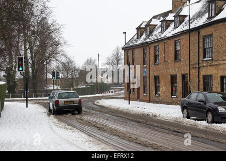 Whittlesea Road Thorney in the snow winter Thorney church place of worship cars and street in the snow snowy weather in Thorney Stock Photo