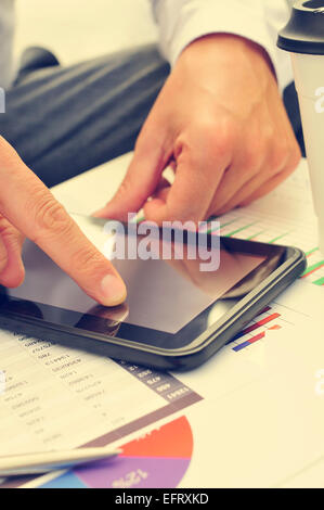 closeup of a young businessman using a tablet computer on a table full of charts Stock Photo