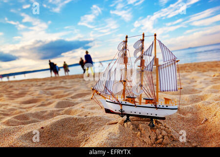 Ship model on summer sunny beach at sunset, ocean in the background. Travel, voyage, vacation concepts Stock Photo