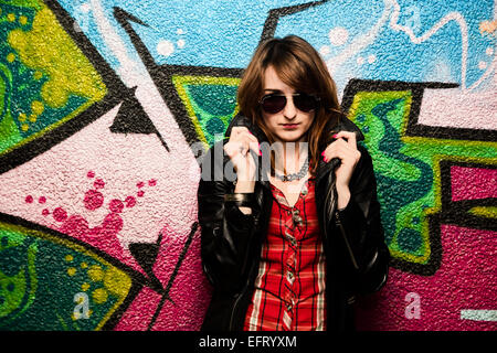 Stylish fashionable girl posing against colorful graffiti wall. Fashion, trends, subculture Stock Photo