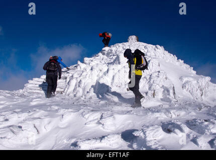 Walkers on the Summit of Snowdon, the highest mountain in England and Wales, in winter conditions Stock Photo