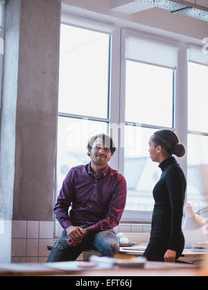 Indoor shot of young people talking in office. Executives discussing work. Stock Photo