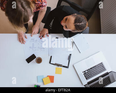 Top view of two young woman working together on a new business project. Businesswoman working on a document at desk in office. Stock Photo