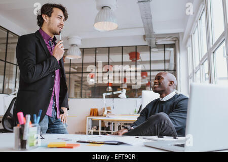 Two young office workers discussing work in office. Office manager with colleague. Stock Photo