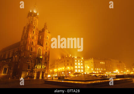 Market square in Cracow at misty night with St. Mary's Basilica with golden sky Stock Photo
