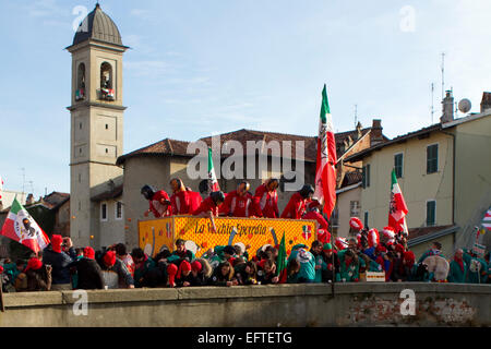 A cart crosses the ancient bridge over river Dora as opposing team throws oranges during 'Battle of the Oranges' in Ivrea Stock Photo